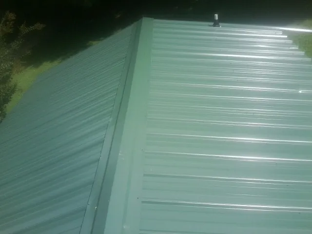 New green metal panels meeting at the ridge of a roof — Flat Roof Repair work by our crew in Shelly