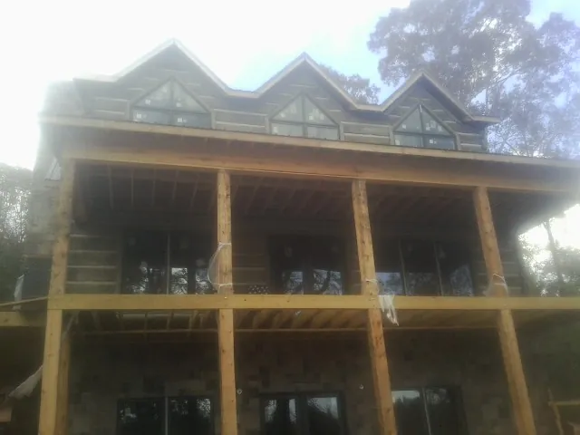 Dormers and porch framing on a large log home under construction — Roof Coating work by our crew in Shelly
