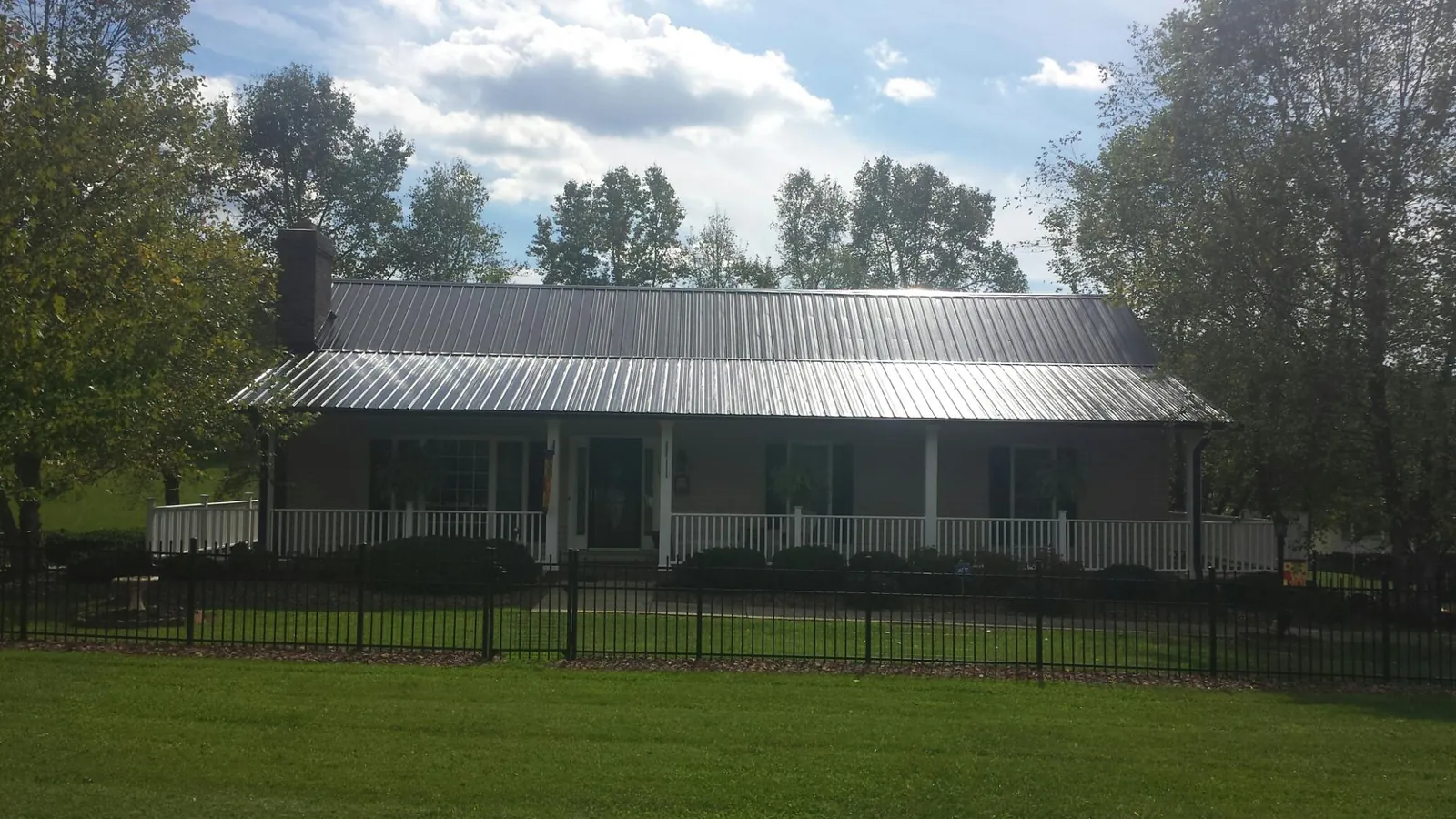 Gray metal roof on a brick ranch with a full width front porch — Gutter Guard Installation work by our crew in Shelly
