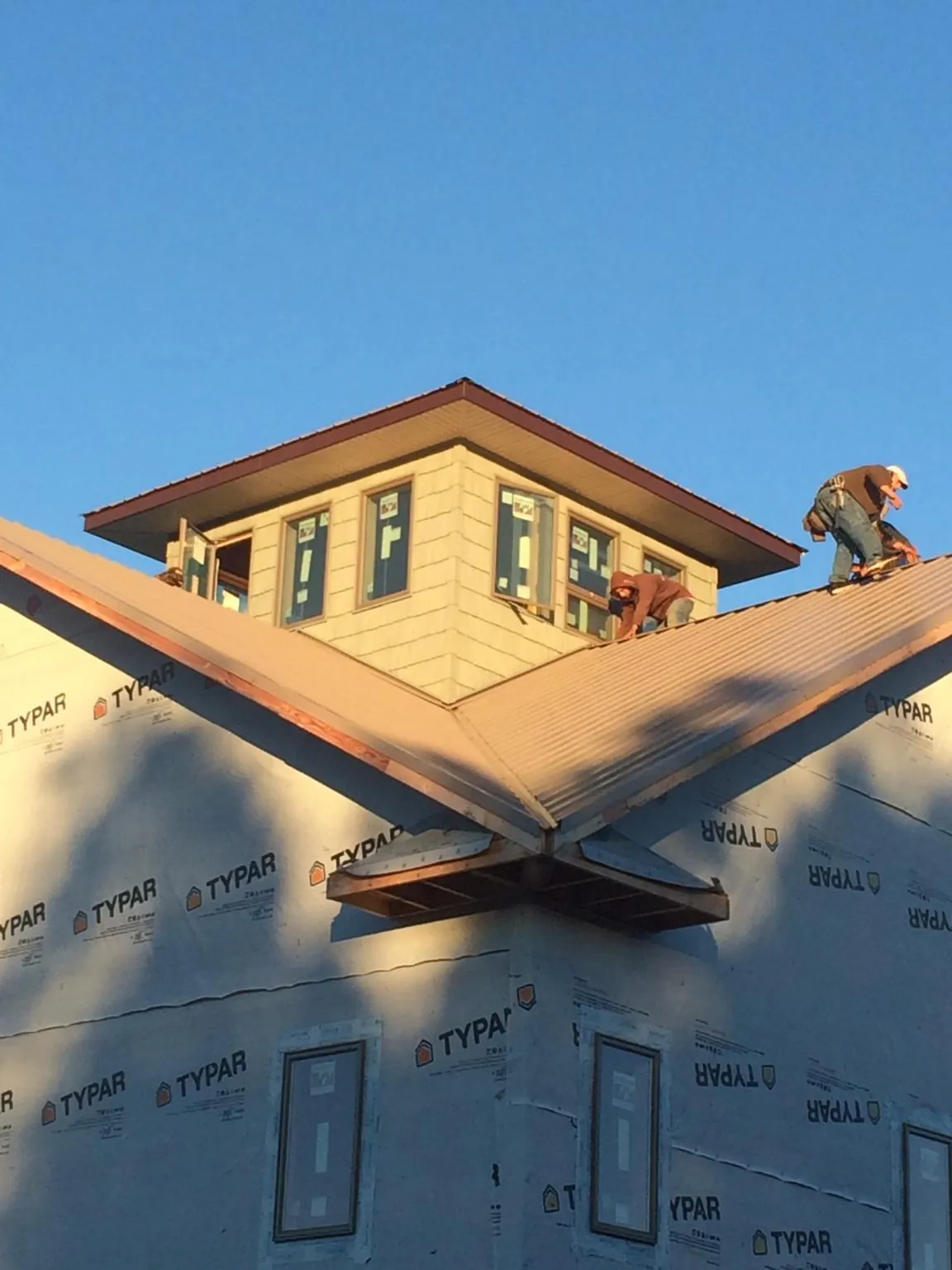 Roofers working around a rooftop cupola on a new metal roof at sunset — Roof Waterproofing in Shelly by Roofing Brothers